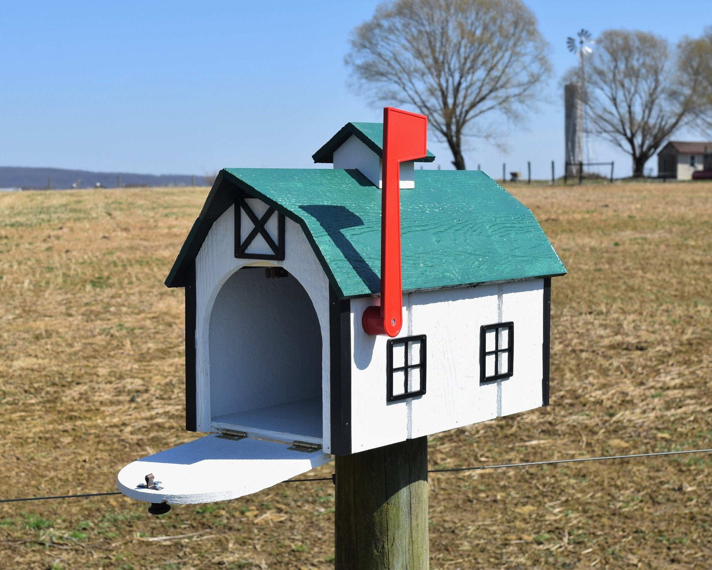 white and green barn mailbox with red flag and open door