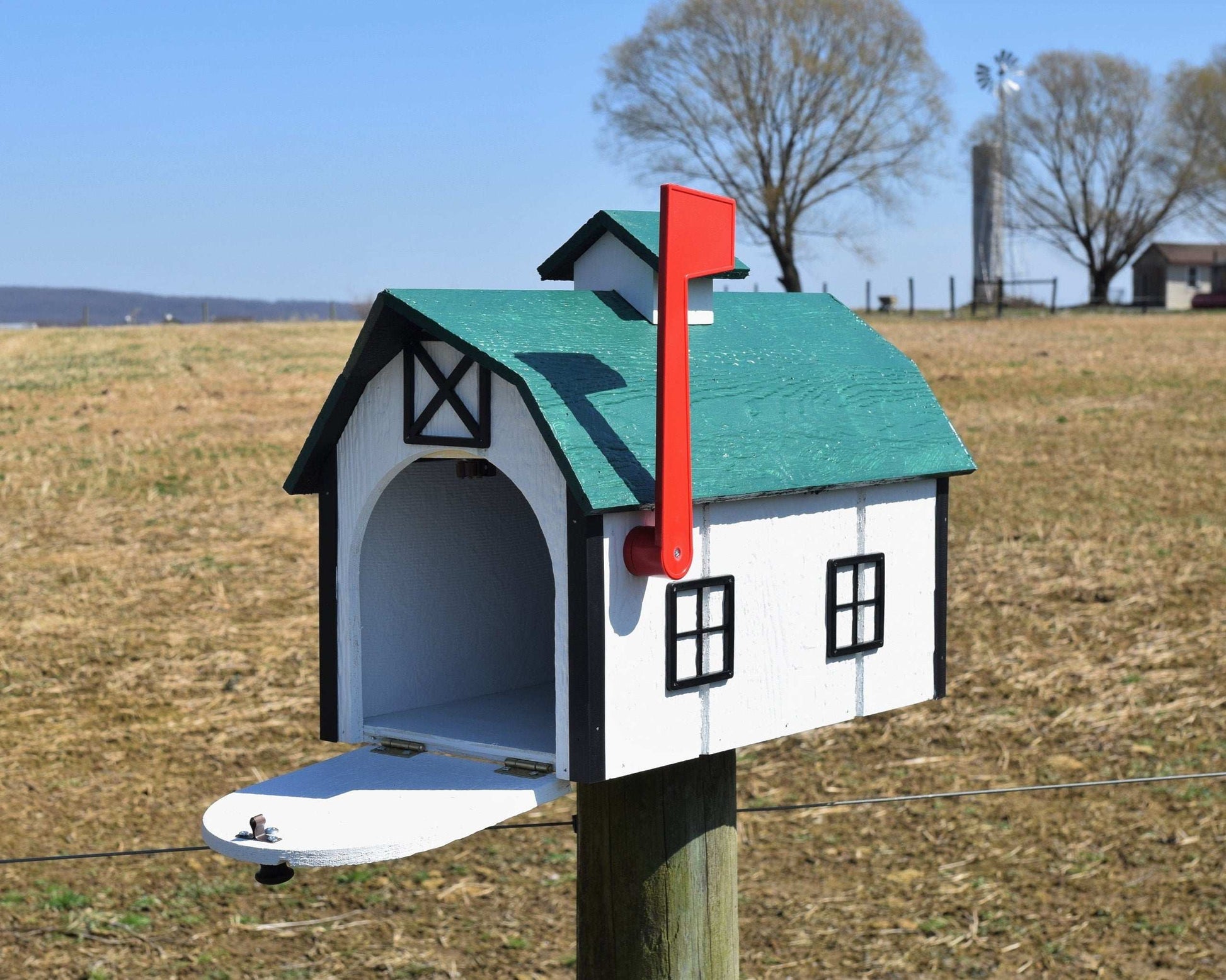 white and green barn mailbox with red flag and open door