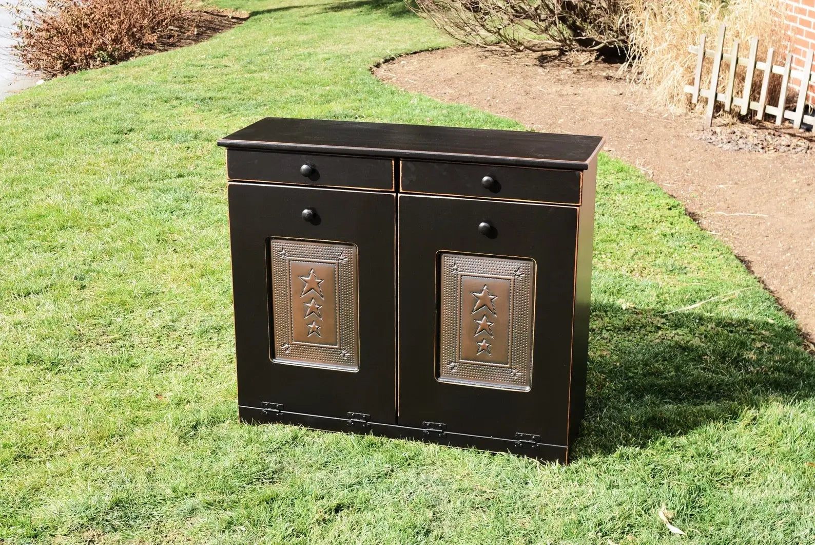 Black double trash bin with copper doors on green lawn