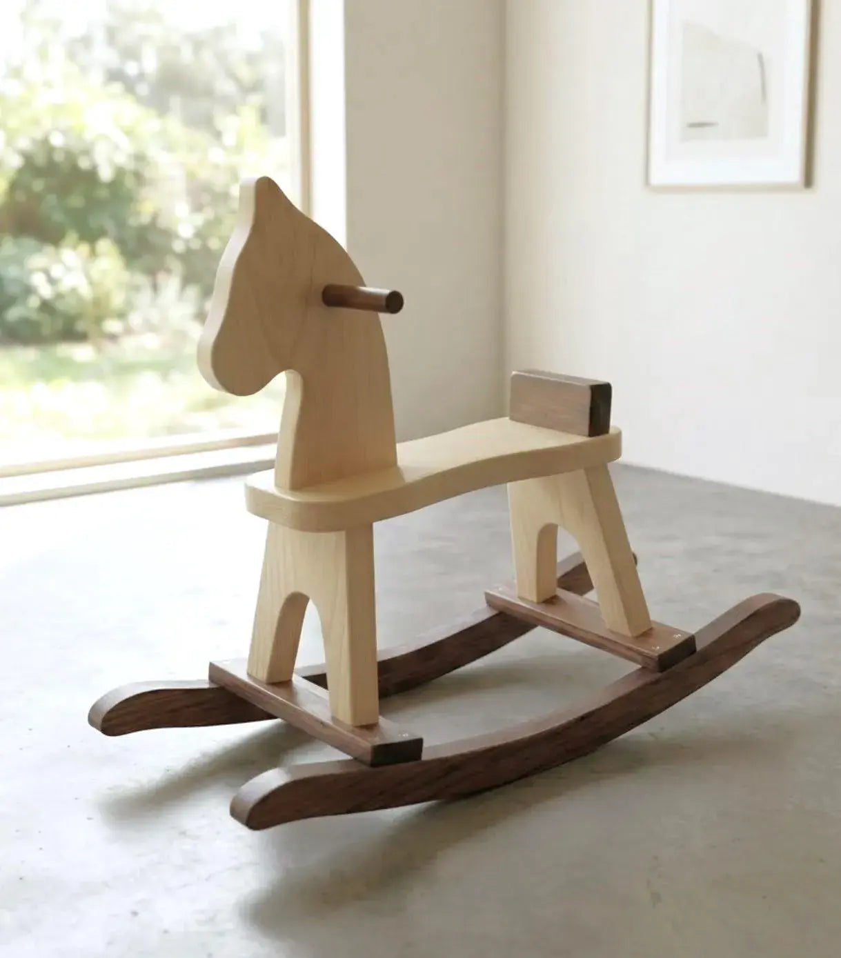 Wooden rocking horse in a room with a window