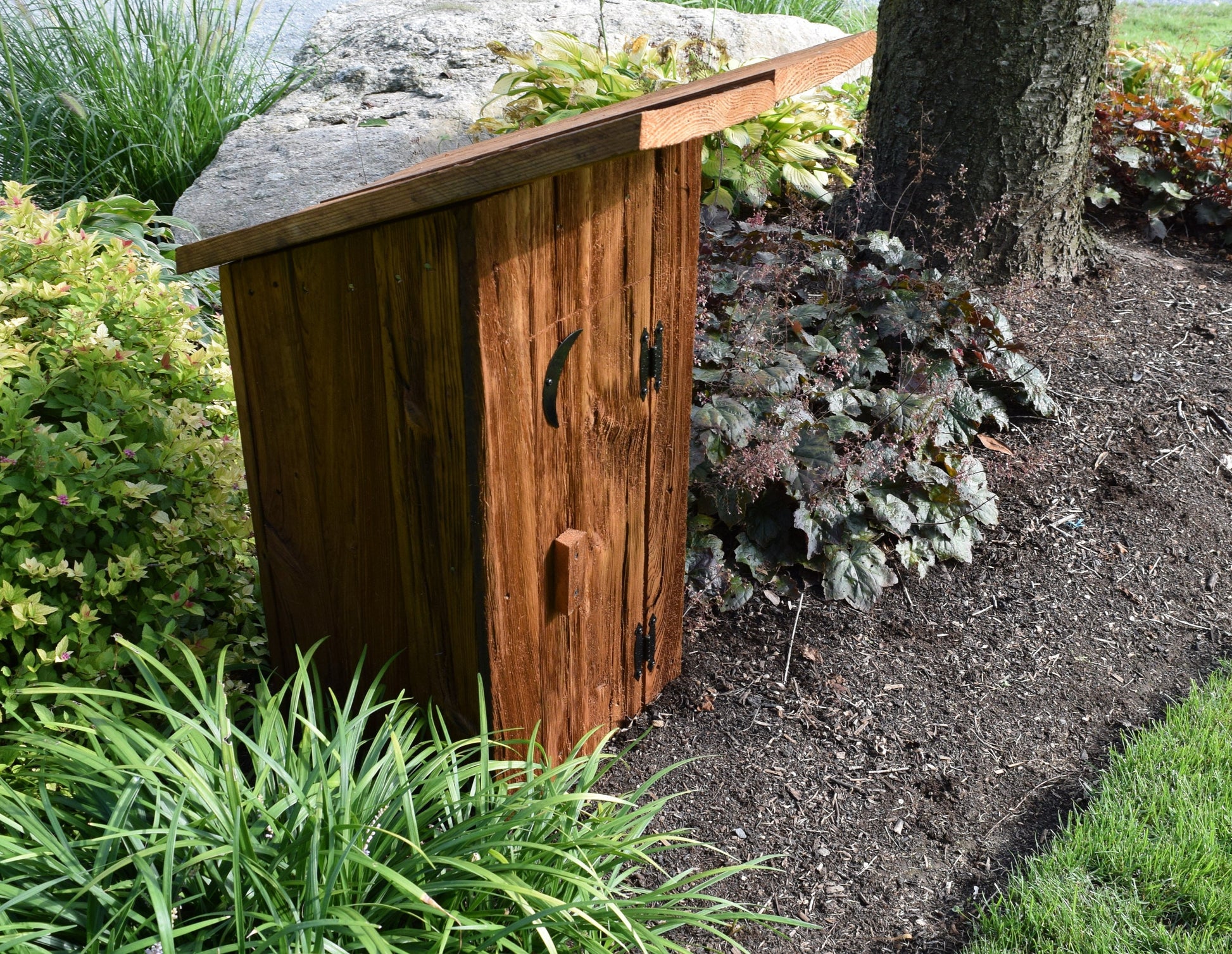 wooden outhouse well cover in flower bed